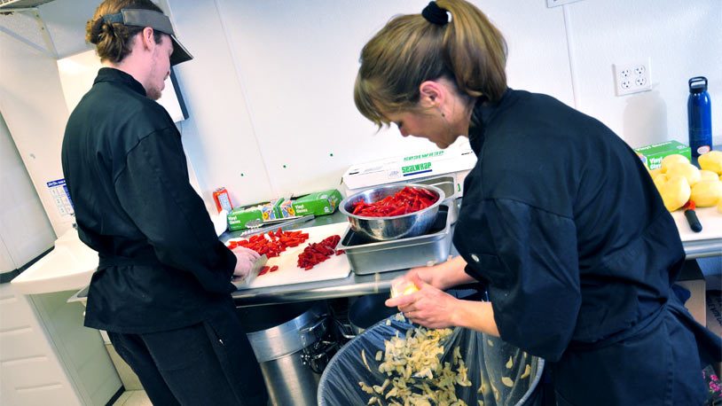 What We Do Two chefs prepping fresh vegetables in the commissary kitchen